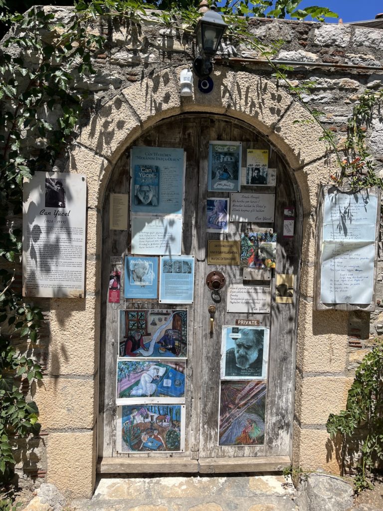 Ein alter Torbogen in Datca, geschmückt mit zahlreichen Plakaten, Hinweisen und Kunstwerken.