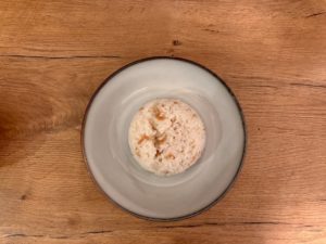 Ein Teller mit einer kleinen Portion Reis auf einem Holztisch.